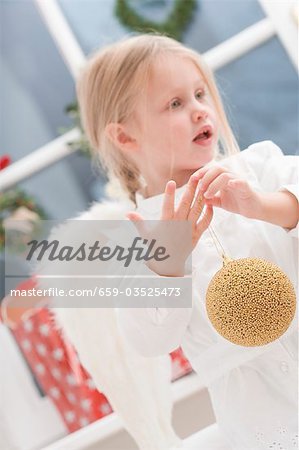 Kleines Mädchen mit Faworki halten Weihnachtskugel