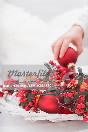 Child placing Christmas bauble in decorated basket