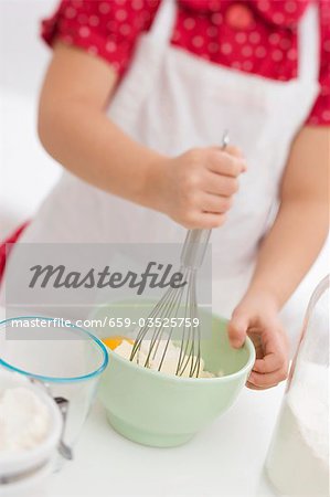 Small girl mixing egg, flour and butter with whisk