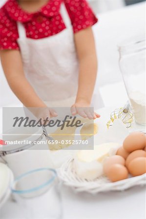 Small girl flattening dough with her hands