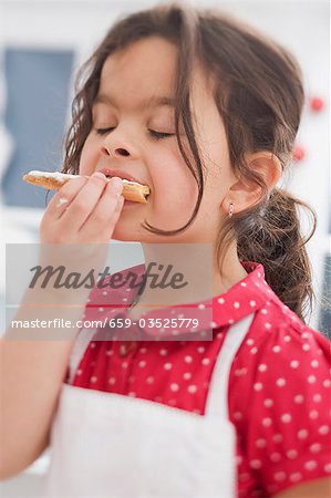 Kleine Mädchen essen Weihnachts-Kekse, die sie selbst gemacht hat