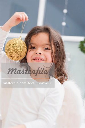 Kleines Mädchen hält Weihnachtskugel gold