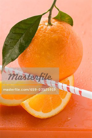 Orange with stalk and leaf, orange wedges, straw