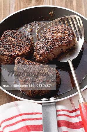 Trois steaks au poivre dans la poêle à frire