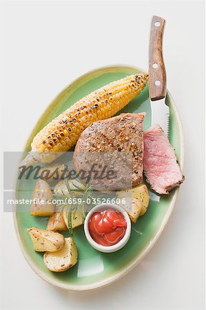 Steak au poivre avec le maïs en épi, pommes de terre rôties & ketchup