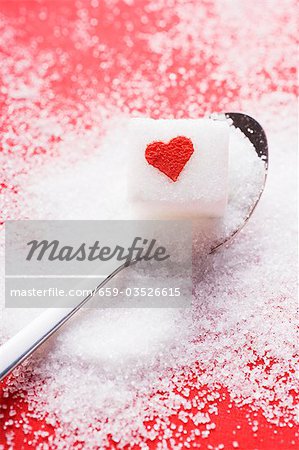 Sugar cube with red heart on spoon Sugar cube with red heart on spoon