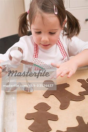 Small girl placing chocolate biscuits on baking tray