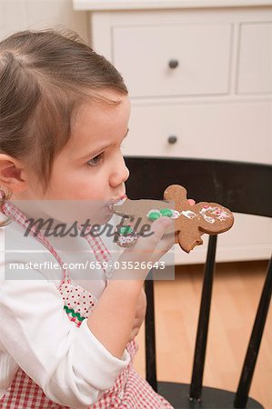 Small girl eating gingerbread man