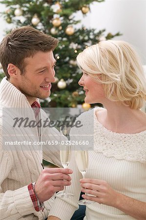 Homme & femme tinter les verres de vin mousseux (Noël)