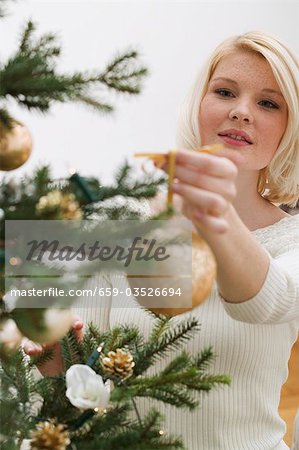 Woman hanging gold bauble on Christmas tree