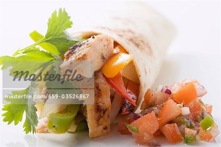 Wrap filled with chicken and pepper, salsa beside it