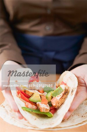 Hands folding a chicken-filled tortilla