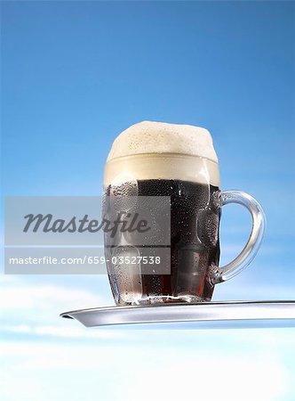 Dark beer in glass mug on tray