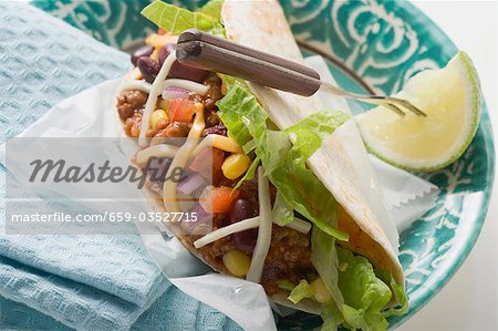 Mince taco with cheese, lime wedge on fork