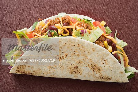 Taco gefüllt mit Hackfleisch & Käse auf braunen Hintergrund