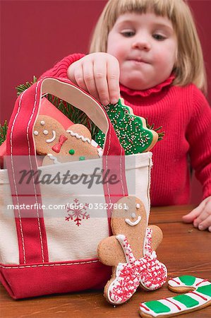 Small girl taking Christmas biscuit out of bag