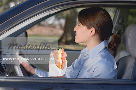 Junge Frau Croissant im Auto Essen
