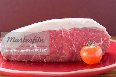 Fresh beef and cherry tomato on red plate