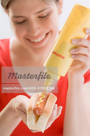 Jeune femme chausser moutarde à Hot-Dog