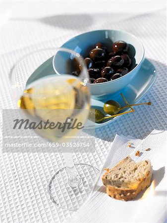 Olives, câpres, pain et verre de vin blanc