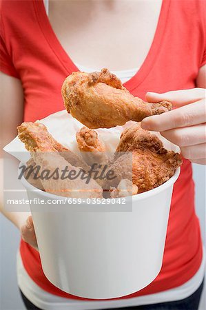 Frau hält frittierte Hähnchenkeulen