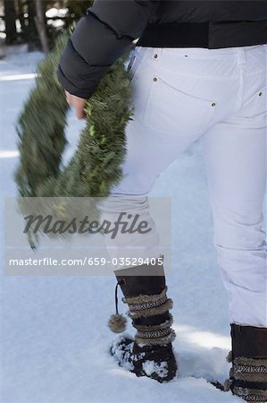 Person carrying a Christmas wreath in the snow