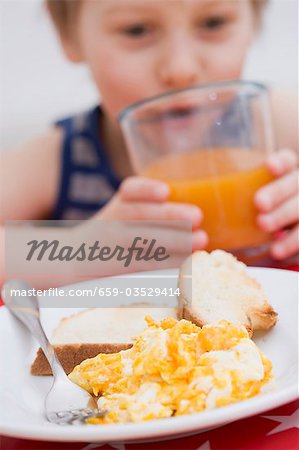Rührei, Ei & Toast, kleiner Junge im Hintergrund Saft trinken