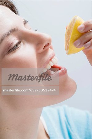 Jeune femme, presser le jus de citron dans sa bouche