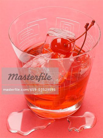 Manhattan with cocktail cherries and ice cubes