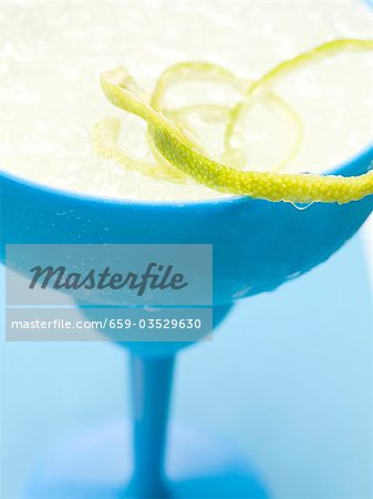 Frozen Margarita with lime zest in blue glass Frozen Margarita with lime zest in blue glass
