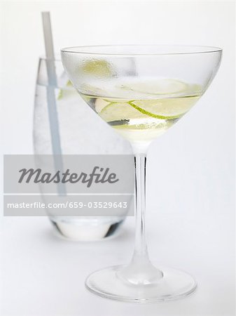 Boire avec des tranches de citron vert, verre d'eau à l'arrière-plan Boire avec des tranches de citron vert, verre d'eau à l'arrière-plan