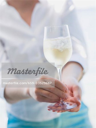 Femme tenant le verre de vin blanc avec des cubes de glace à l'extérieur