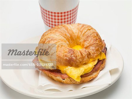 Croissant rempli de œufs brouillés, fromage et bacon