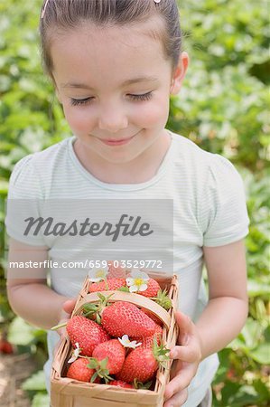 Little girl holding basket of strawberries