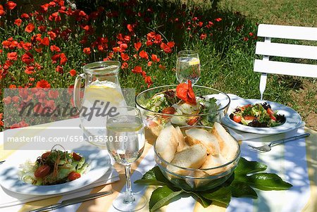 Salad and bread on laid table in summery garden