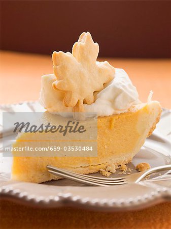 Piece of pumpkin pie with cream and pastry leaf