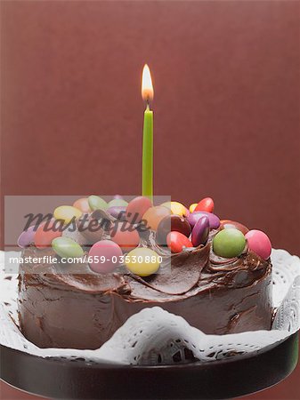 Chocolate cake with coloured chocolate beans and candle
