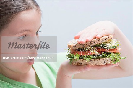 Fille regardant un gros sandwich
