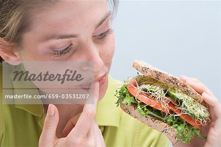 Junge Frau hält Sandwich und leckte den finger