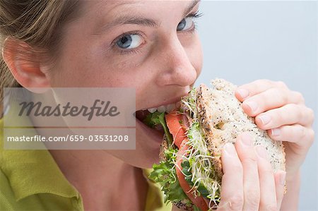 Woman biting into a sandwich with enjoyment