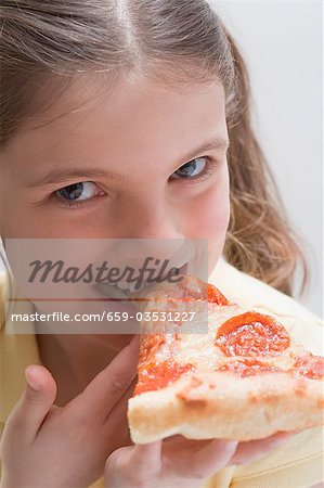 Mädchen beißt in ein Stück Pizza salami