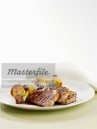 Grilled pork steaks with roast potatoes and olives