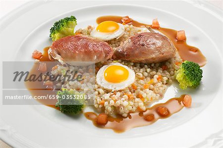 Quail breasts on pearl barley with quails' eggs & bacon sauce