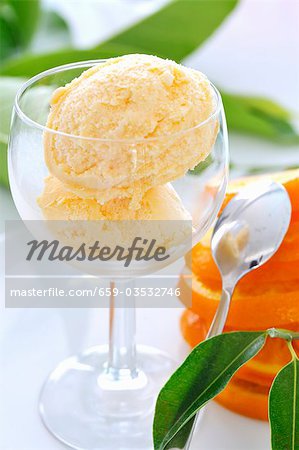 Two scoops of orange ice cream in a glass