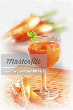Karottensaft in Glas, frische Karotten, daneben