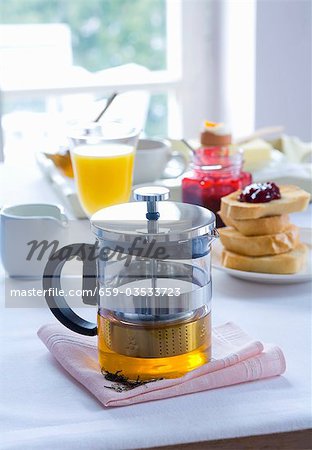 Teekanne, Toast und Orangensaft auf einem Frühstückstisch