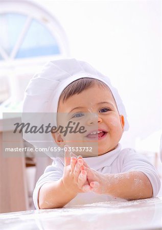 Petite fille à la toque de mains farineuse