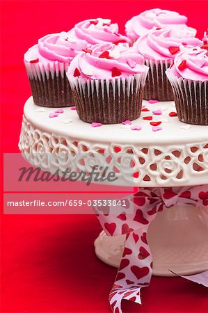Petits gâteaux au chocolat avec un glaçage rose sur le stand de gâteau
