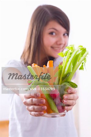 Mädchen hält eine Schale mit Gemüsesticks mit Radieschen