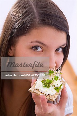 Mädchen essen Knäckebrot mit Hüttenkäse und Kresse